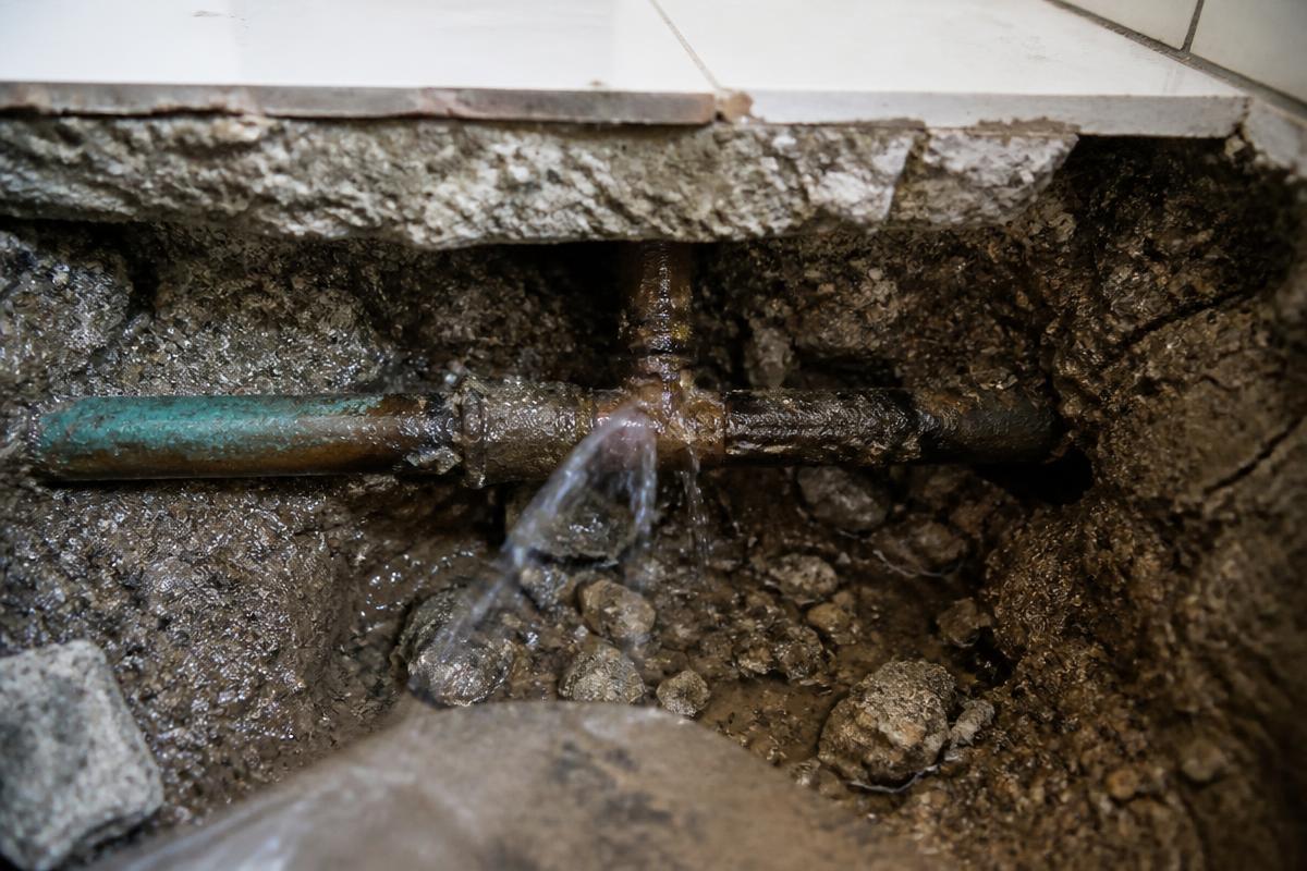 Aufgestemmter Boden mit freiliegender undichter Wasserleitung