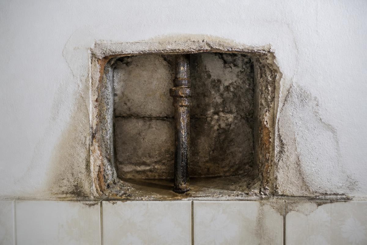 Aufgestemmte Wand mit korrodiertem und undichtem Rohr
